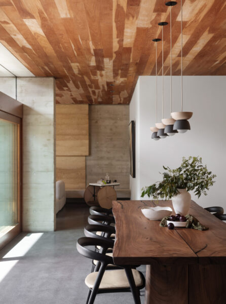 Nature-inspired home interior with flowing organic forms, clay and linen materials, living wall plants and large windows connecting indoor spaces with the natural environment.